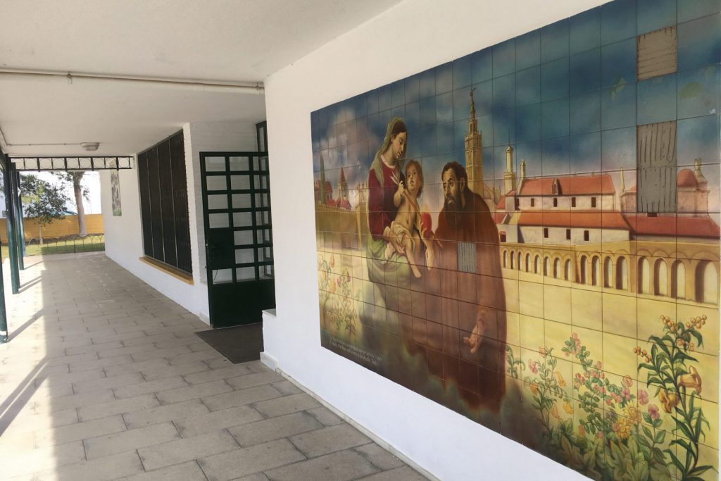 Mural de cerámica en el porche del colegio, con una escena de la Sevilla histórica