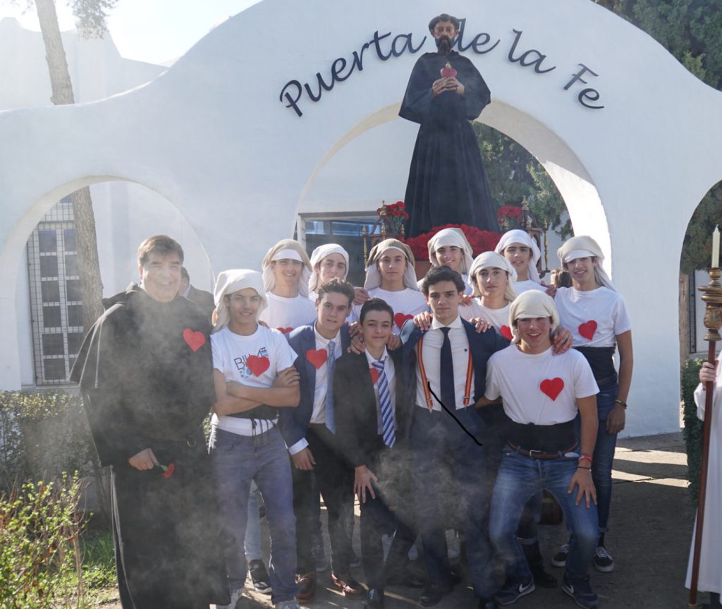 Grupo de alumnos posando bajo un arco blanco con la inscripción «Puerta de la Fe»