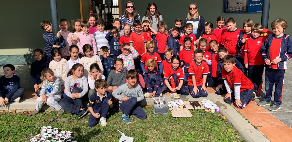 Grupo numeroso de alumnos posando en el césped junto a los trabajos que han hecho