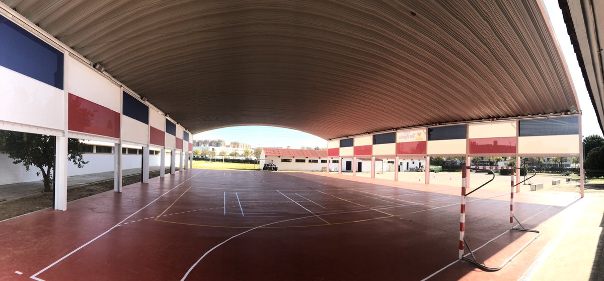 Pista polideportiva cubierta con suelo rojo, porterías y gradas laterales