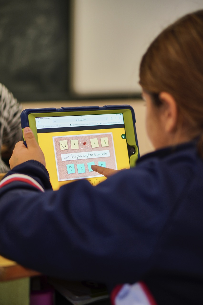 Alumna de Primaria trabajando en un iPad apoyado en el pupitre