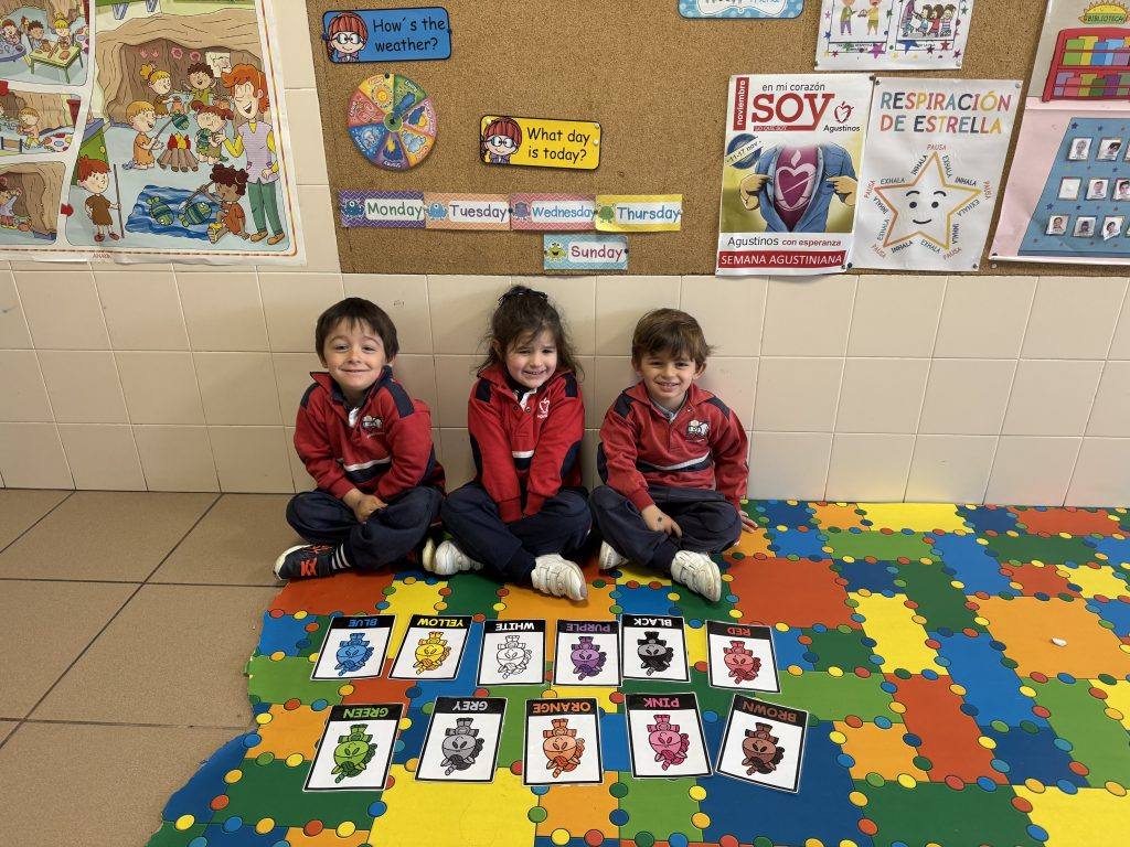 Tres alumnos de Infantil sentados junto a tarjetas de vocabulario en una clase de inglés