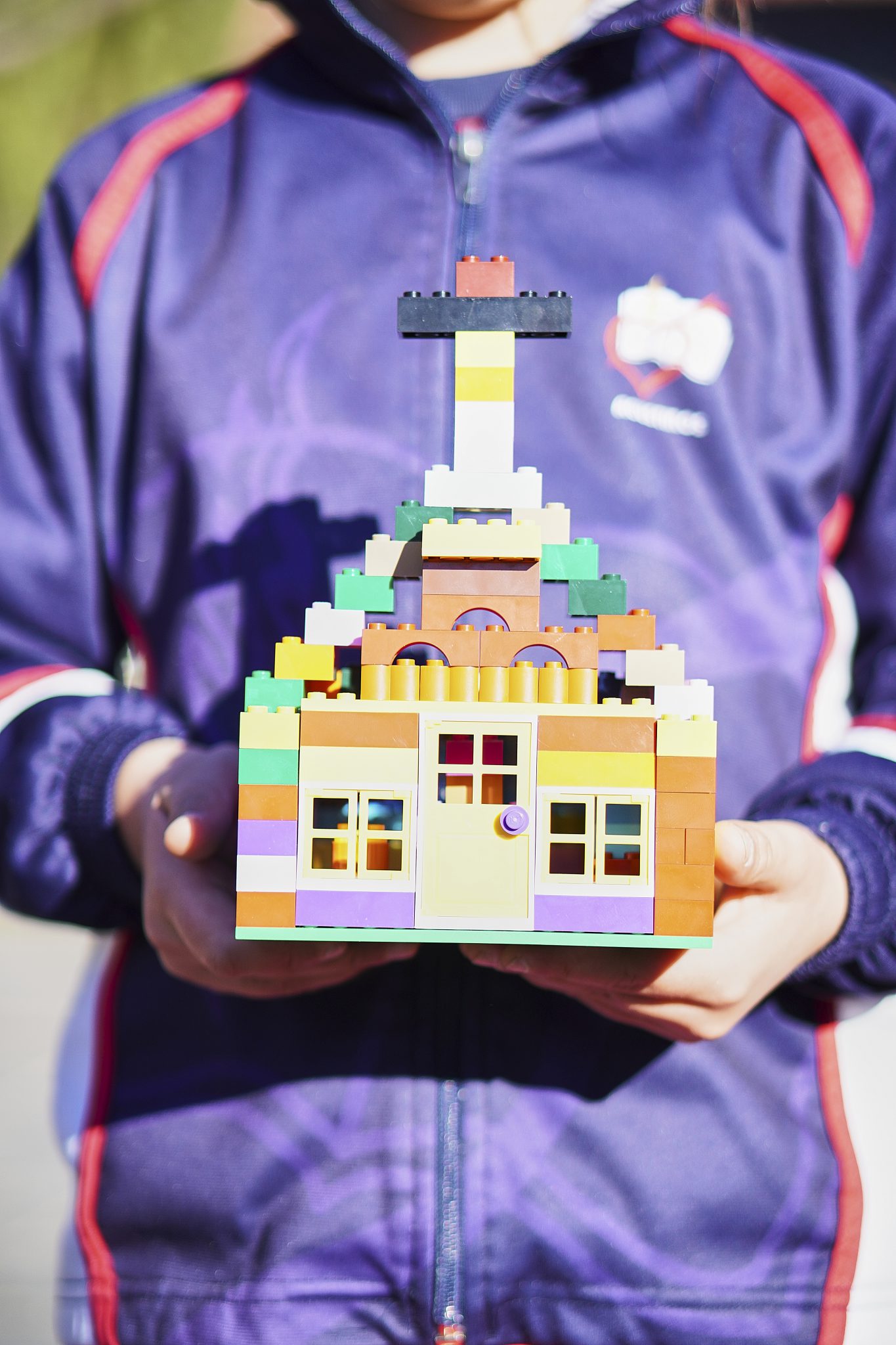 Alumno sosteniendo una maqueta de una iglesia hecha con piezas de construcción