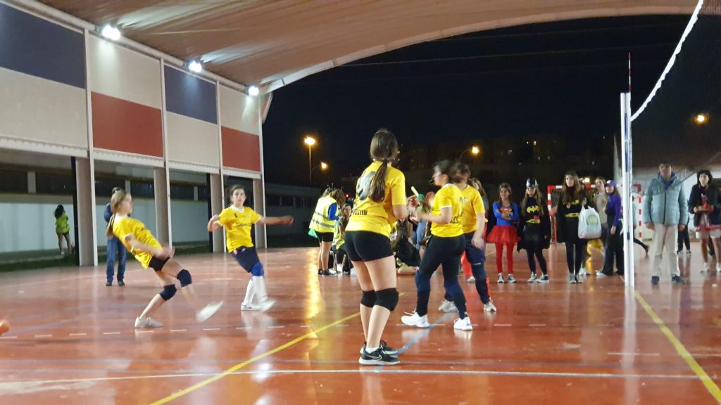 Partido de voleibol en la pista cubierta, de noche, con público en la banda
