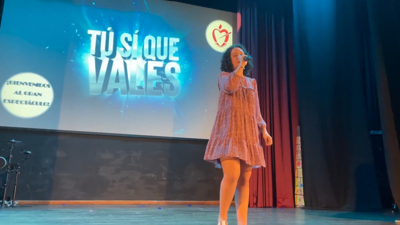 Alumna cantando en el escenario ante un fondo iluminado con el rótulo «Tú sí que vales»