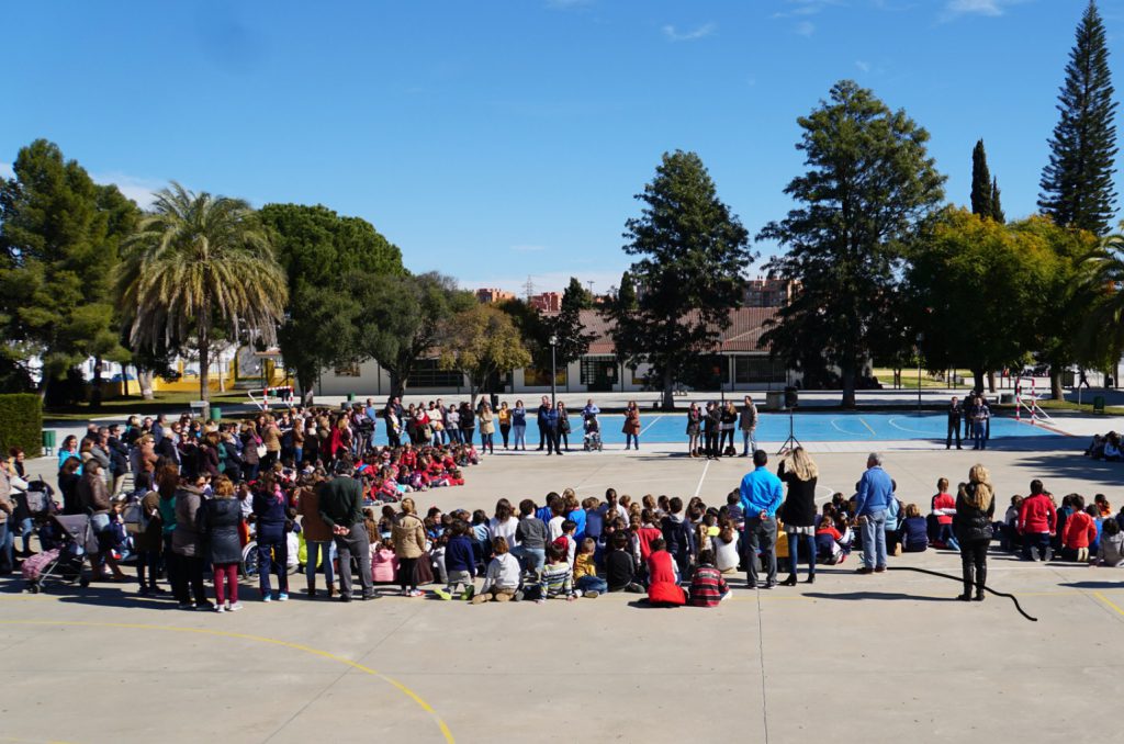 Cientos de alumnos y familias reunidos en el patio del colegio en un día soleado