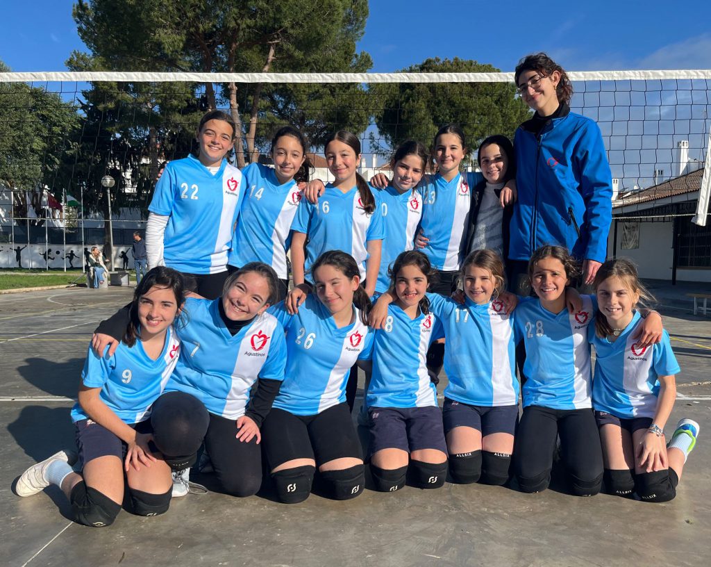 Equipo alevín de voleibol del colegio, posando ante la red