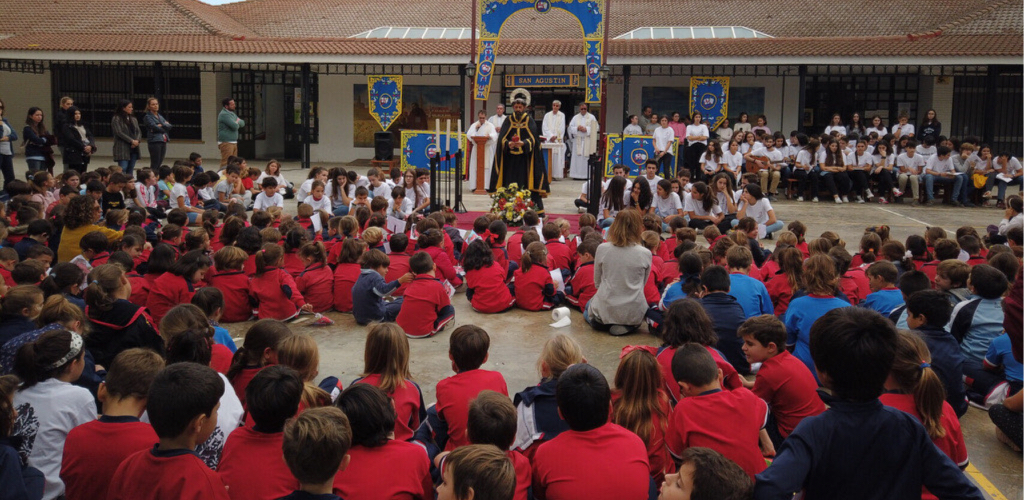 Cientos de alumnos de Infantil y Primaria sentados en el patio durante un acto