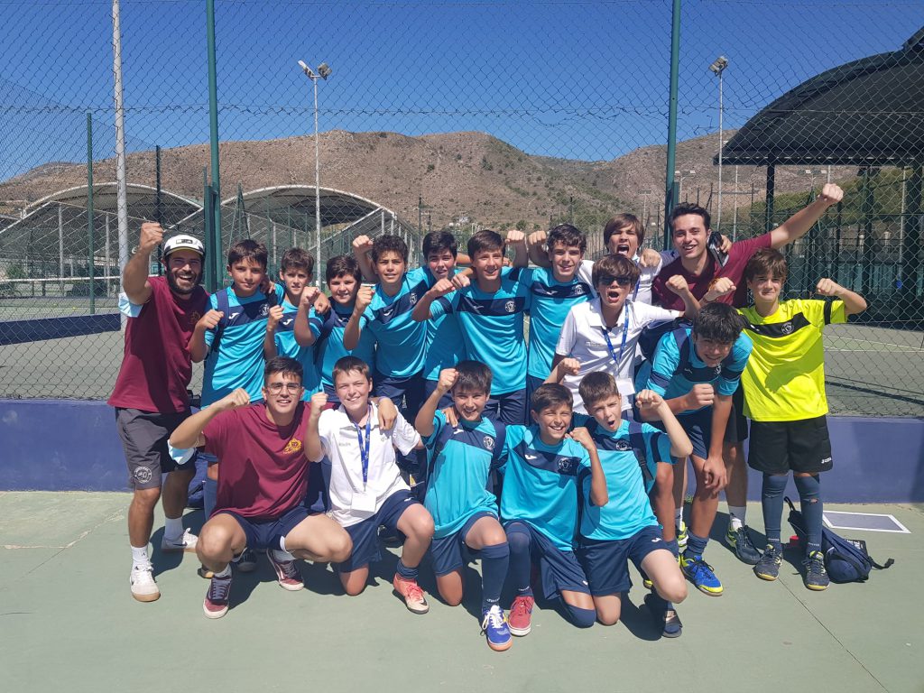 Equipo del colegio celebrando con los brazos en alto en una pista deportiva