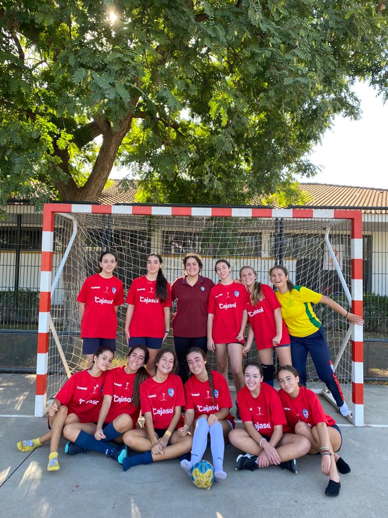 Equipo femenino del colegio, con camiseta roja, posando ante una portería