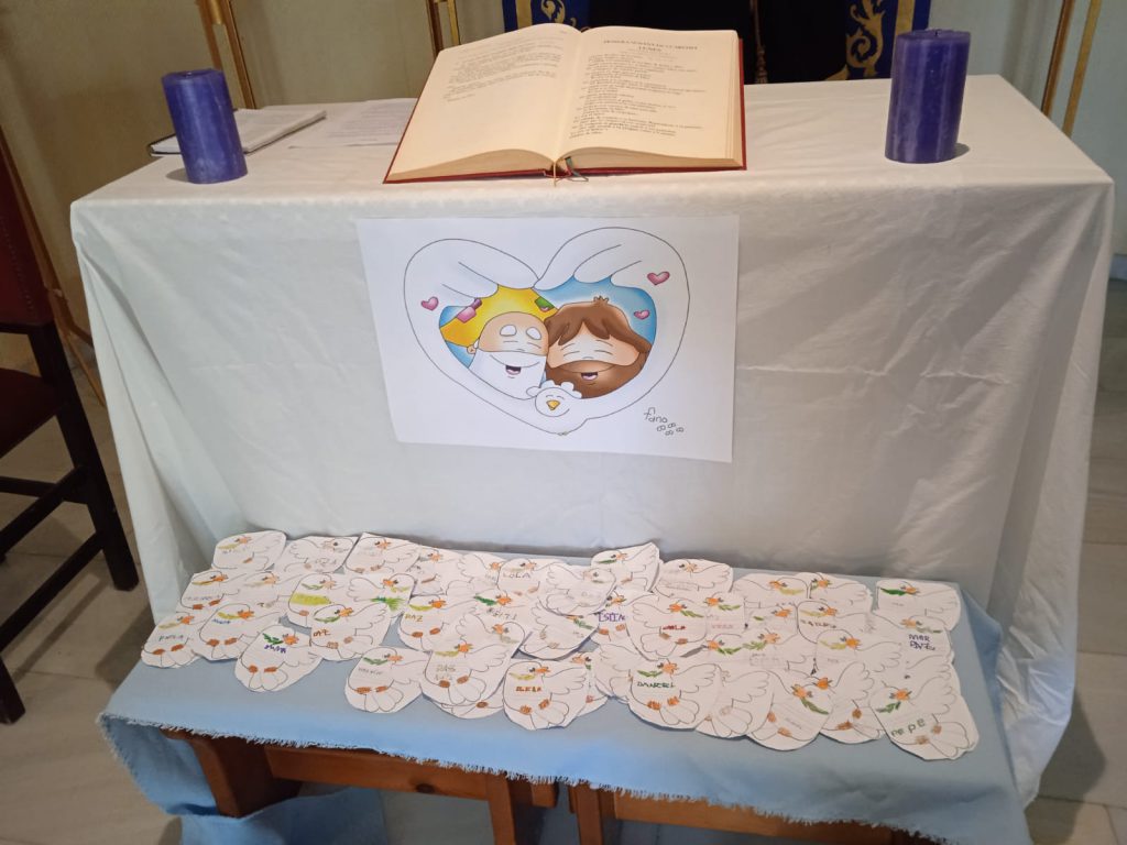 Altar preparado con un libro abierto, dos velas y corazones de papel escritos por los alumnos