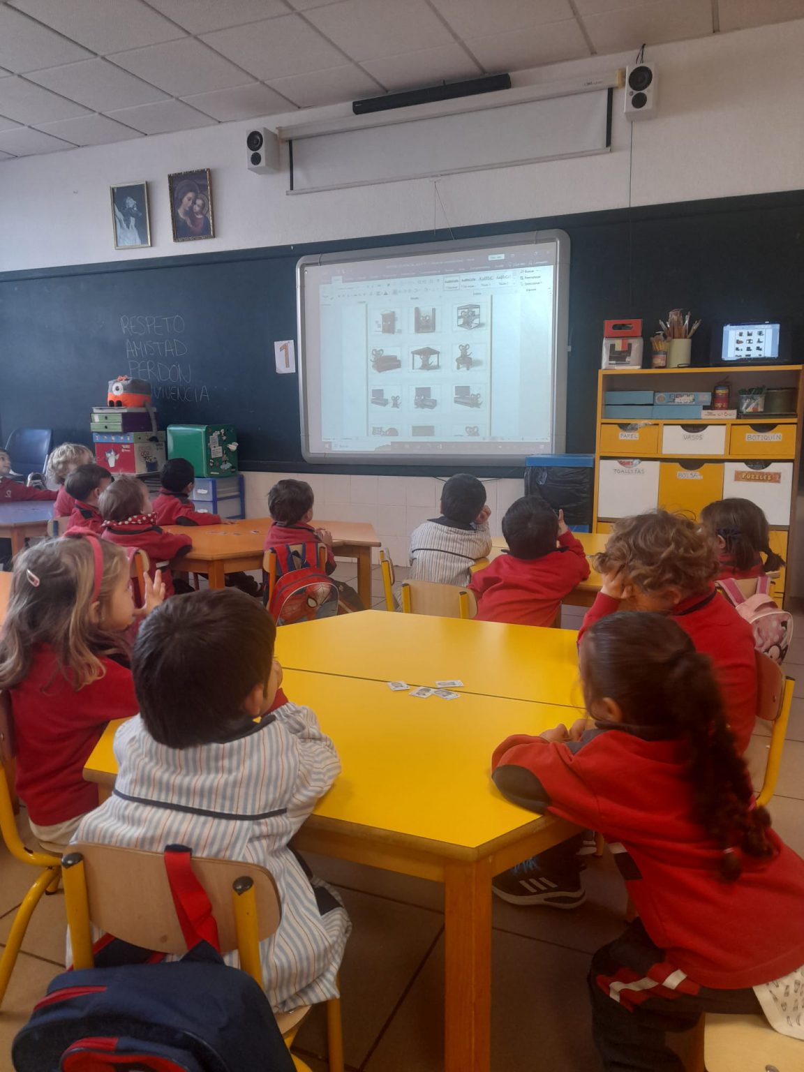 Niños de Infantil trabajando en mesas amarillas, frente a la pizarra digital