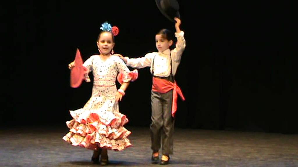 Dos niños vestidos de flamenca y de corto bailando sevillanas