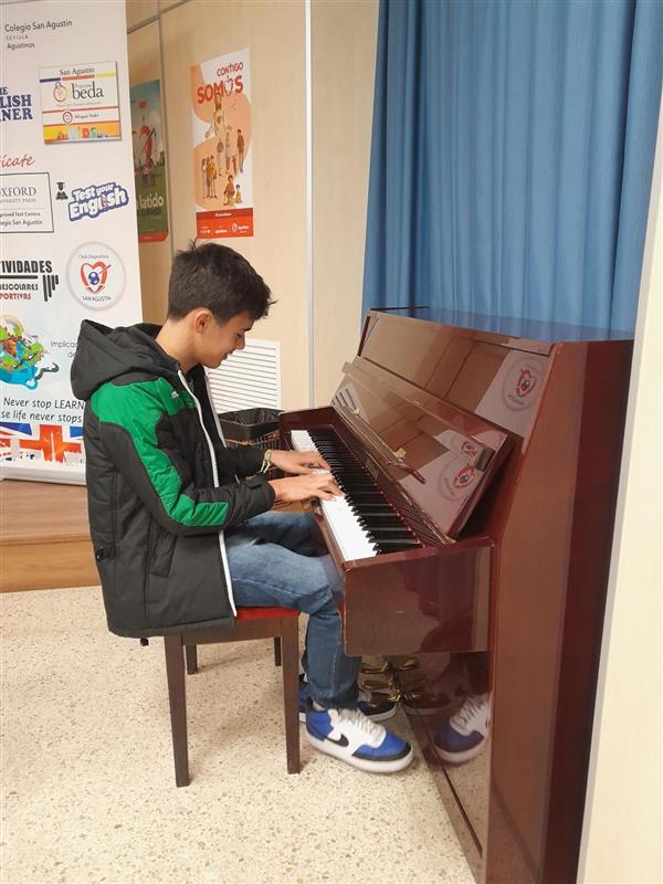 Alumno tocando un piano vertical en un aula del colegio