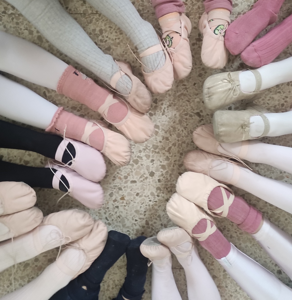 Vista cenital de una docena de pies con zapatillas de ballet formando un círculo