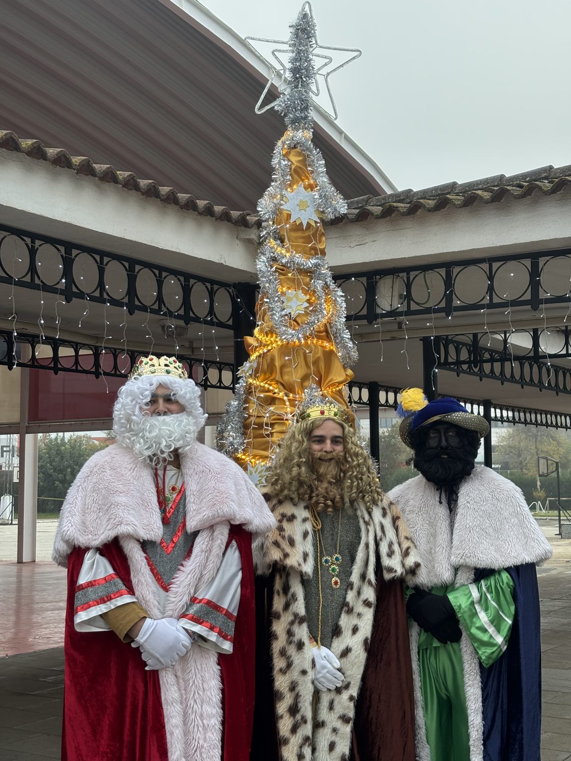 Los tres Reyes Magos, con sus trajes, junto al árbol de Navidad del porche