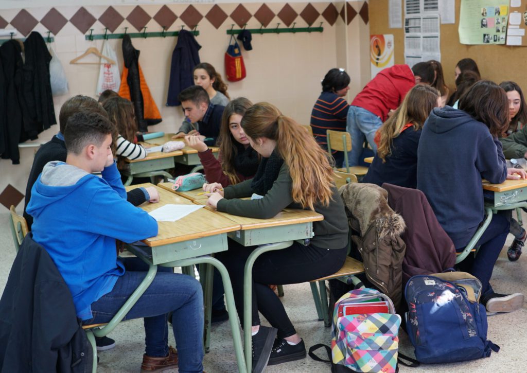 Alumnos de Secundaria trabajando por grupos alrededor de las mesas del aula