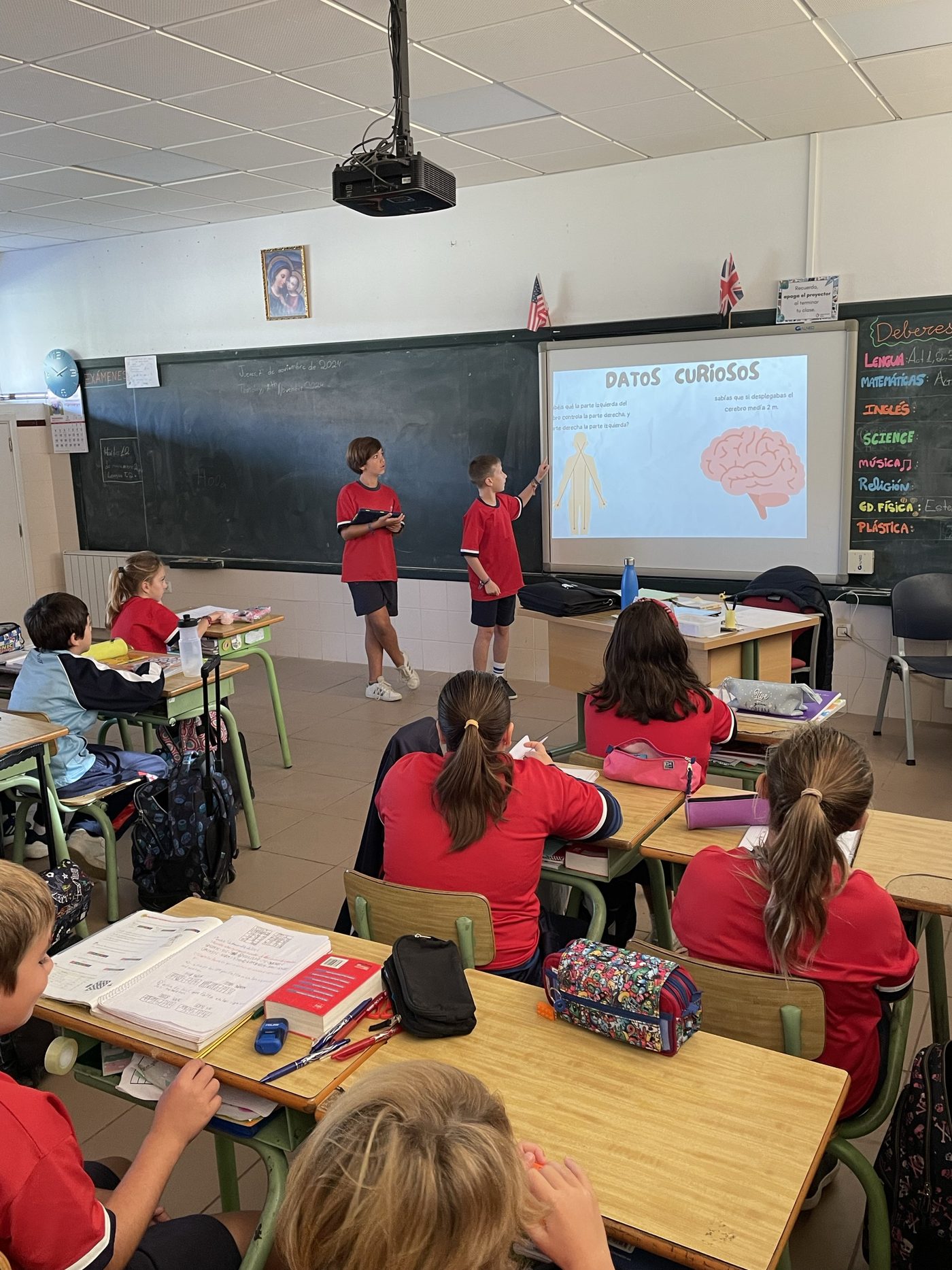 Alumna señalando un esquema proyectado en la pizarra digital del aula