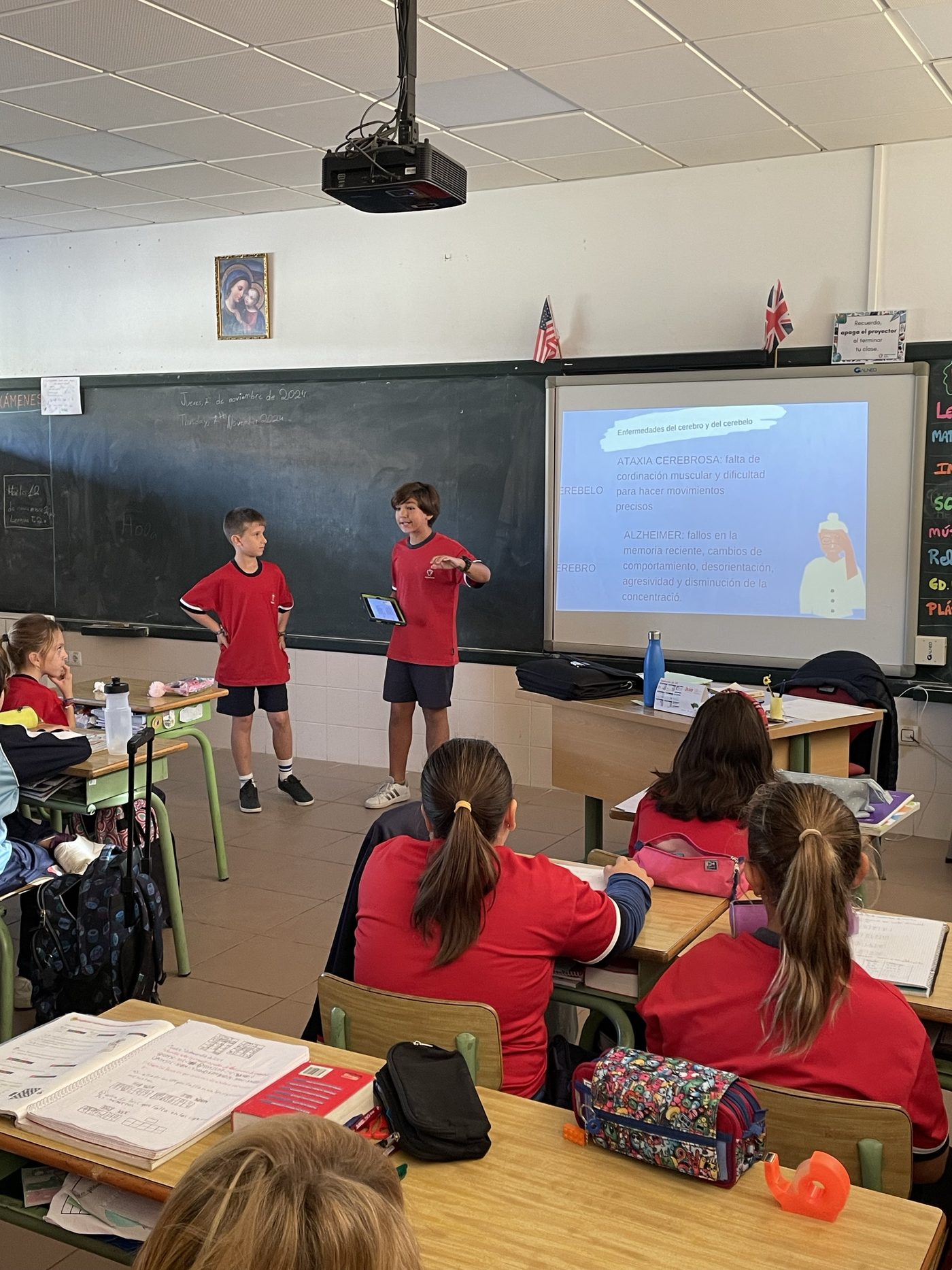 Dos alumnos de Primaria presentando un trabajo ante la pizarra digital, con la clase sentada delante
