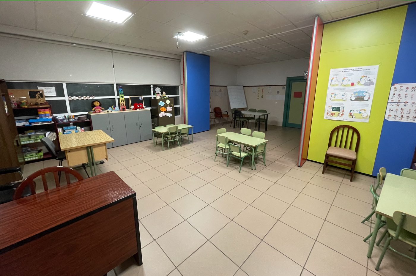 Aula de Educación Infantil vacía, con sus rincones de trabajo y paneles de colores